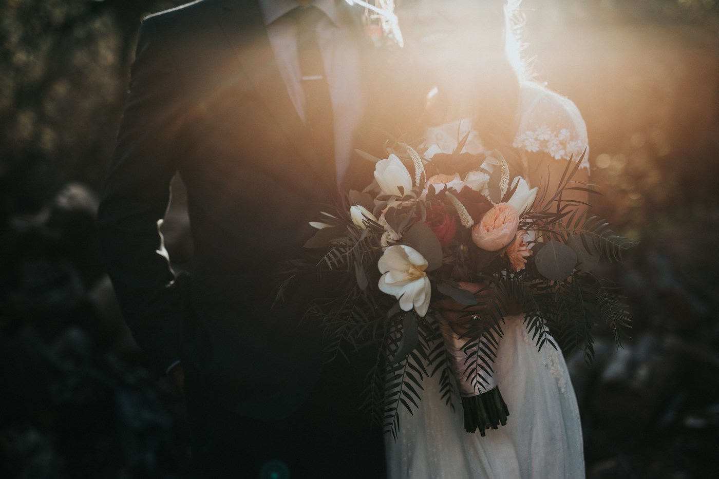 A bride and groom with a bouquet in the afternoon sun
